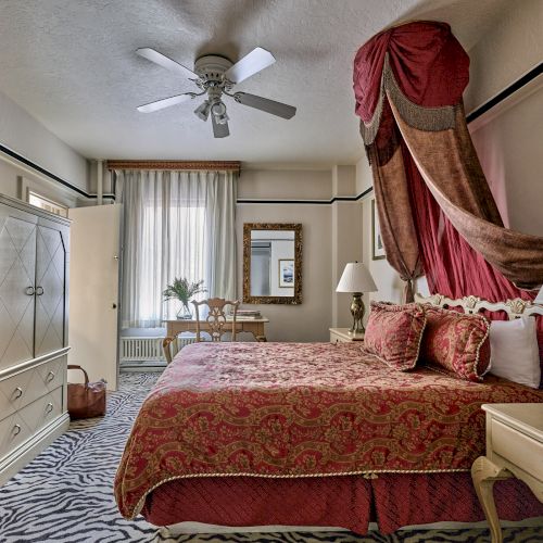 The image shows a luxurious bedroom with elegant drapes, a large bed, a wardrobe, lamps, and a patterned carpet.