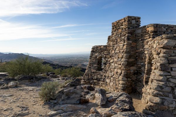 Ancient stone ruins in a desert landscape, with mountains and clear sky visible in the background, creating a serene and timeless scene.