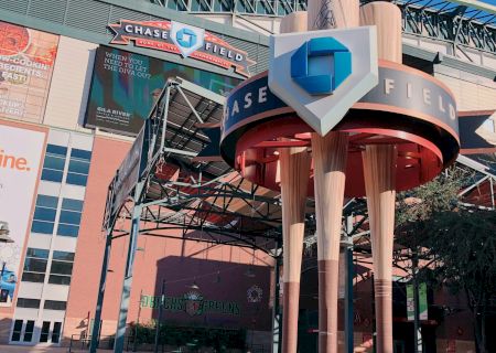 The image shows an exterior view of Chase Field, featuring large decorative baseball bats and the stadium sign.