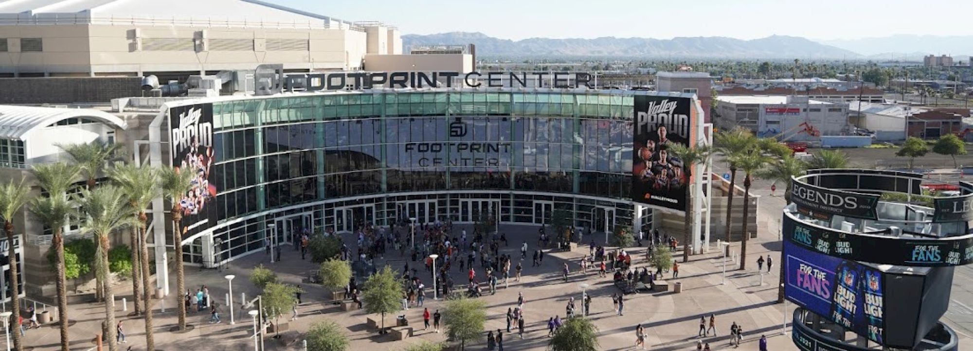 The image shows the entrance to the Footprint Center with people outside and surrounding palm trees.